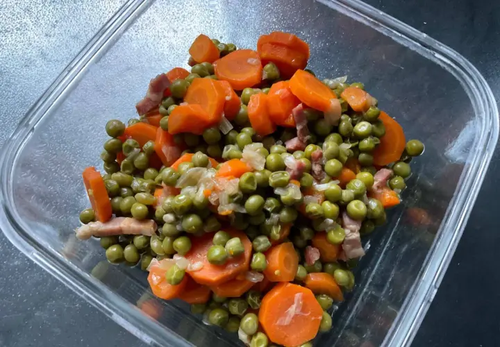Un plat de petit pois carotte, avec des lardons, dans un récipient en verre. Un classique réconfortant.