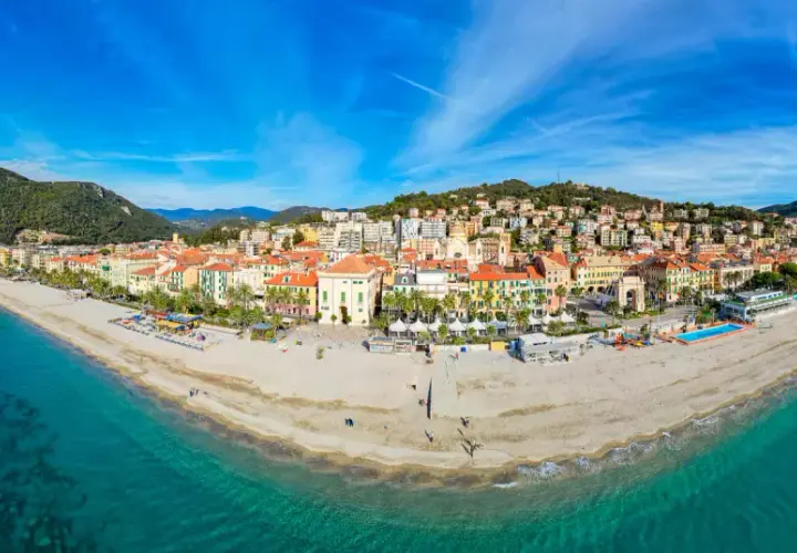 Vue panoramique de la plage et de la ville colorée de Finale Ligure, Italie, sous un ciel bleu éclatant.