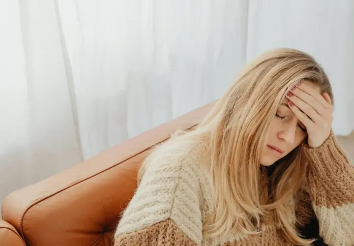 Donna bionda con la mano sulla fronte, forse per un mal di testa. Si chiede a cosa serve il Depakin per alleviare il dolore.