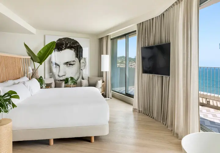 Habitación moderna en el hotel Terramar Sitges con cama king, arte de gran tamaño y vistas al mar.