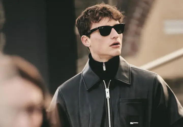 Joven con gafas de sol y chaqueta de cuero, luciendo modernos cortes de pelo hombre joven.
