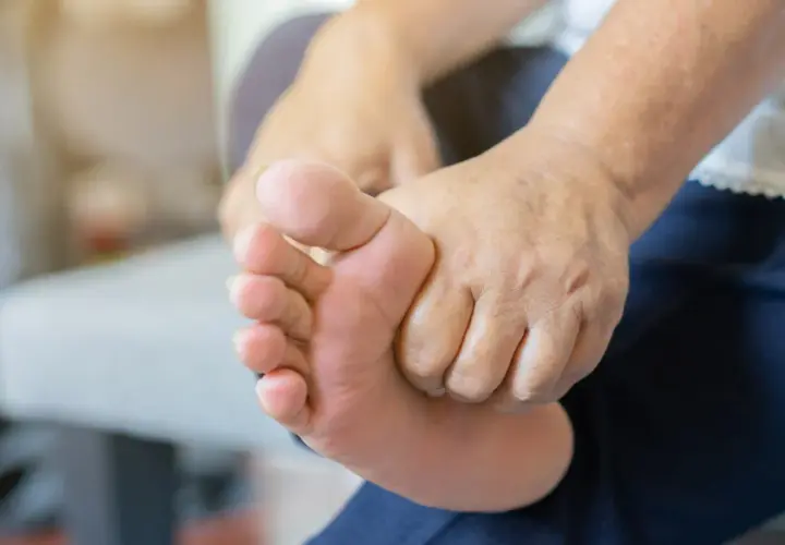 Dłoń masuje bolącą stopę, być może z powodu nadmiaru potasu.