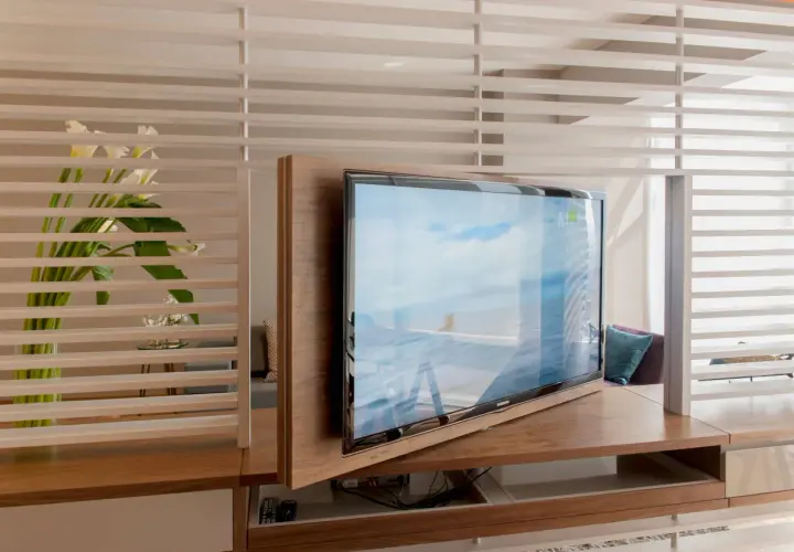 Ein moderner Wohnraum mit einem drehbaren Fernseher, der sich elegant in die Holzverkleidung integriert. Callas und dezente Beleuchtung schaffen eine ruhige Atmosphäre, ideal, um den Fernseher verstecken zu können.