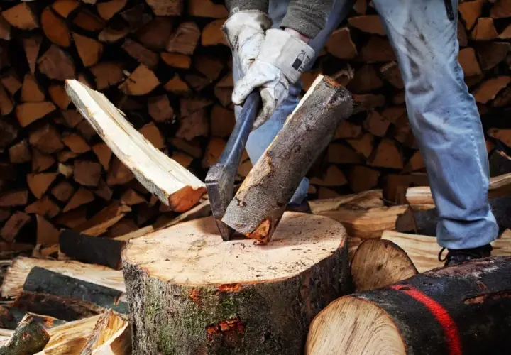 Mann spaltet Holz mit Axt. Mit der richtigen Technik kann man den Holzspalter schneller machen und effizienter arbeiten.