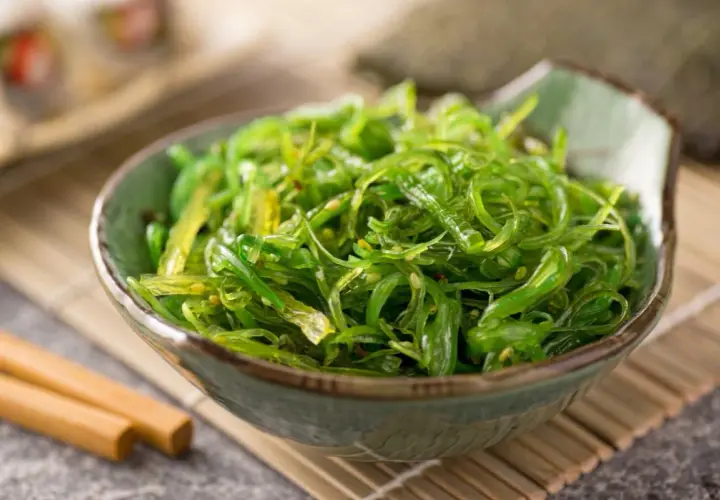 Insalata di alghe wakame in una ciotola, con bacchette. Informazioni su alga wakame controindicazioni.
