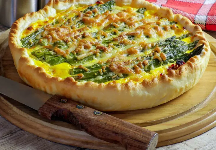 Tarta ze szparagami i serem na kruchym cieście, obok nóż.