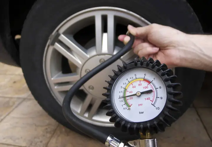 Manometro collegato a una ruota d'auto, dove è scritta la pressione dei pneumatici.