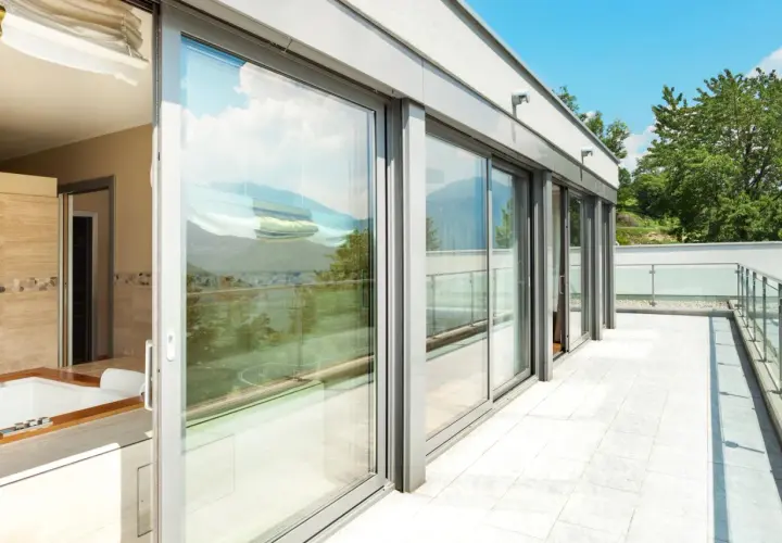 Nowoczesny balkon z przeszklonymi drzwiami i widokiem na góry.