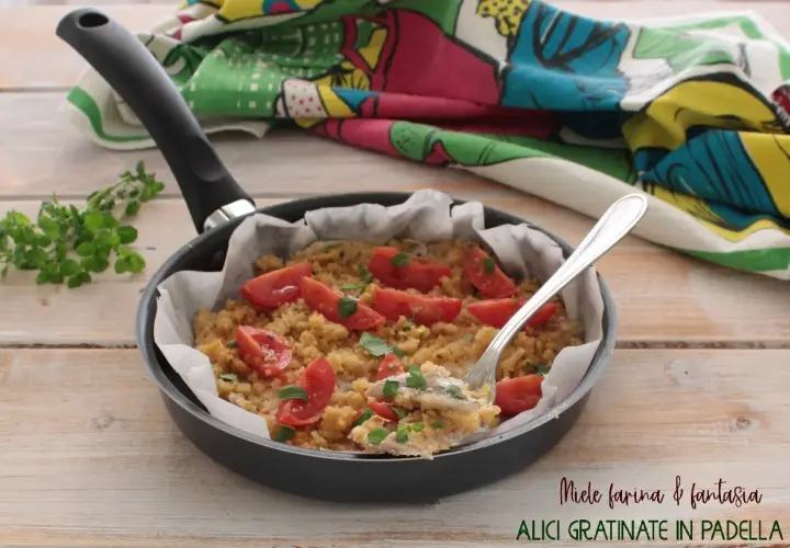 Alici gratinate in padella con pomodorini e pangrattato, un piatto semplice e gustoso.