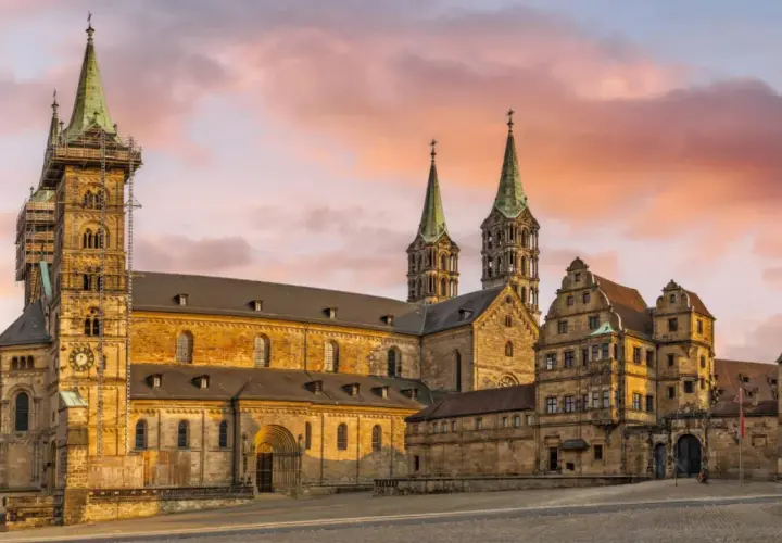 Bamberg Altstadt: Majestätischer Kaiserdom mit Türmen im Abendlicht, umgeben von historischen Gebäuden.