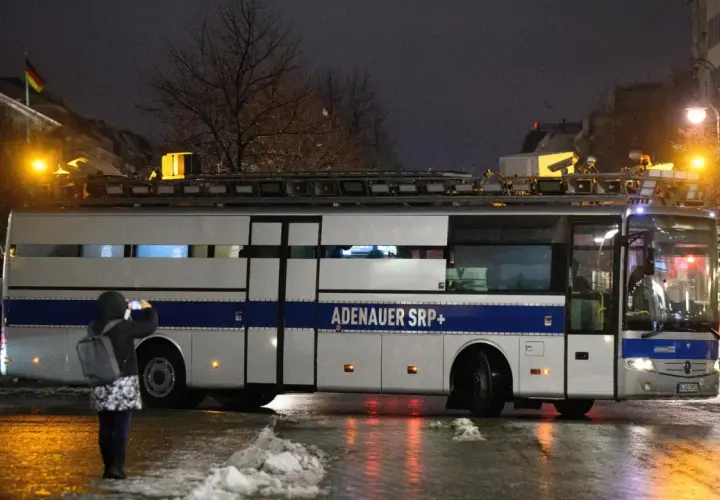 Ein Bus mit der Aufschrift "ADENAUER SRP+" steht im Dunkeln. Eine Person fotografiert ihn.
