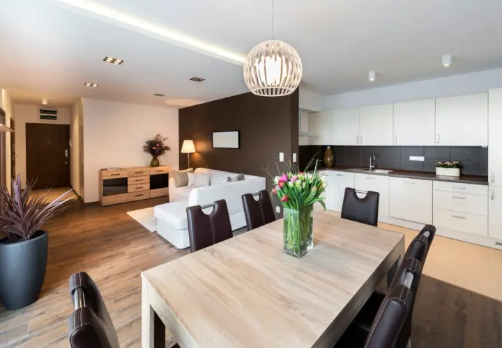Salon moderne avec cuisine ouverte, table en bois et tulipes. Idéal pour un primo accédant cherchant un espace de vie lumineux et fonctionnel.