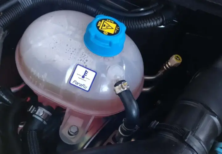 Depósito de expansión del refrigerante de un coche. El símbolo de termómetro y "Paraflu" indican el líquido anticongelante.
