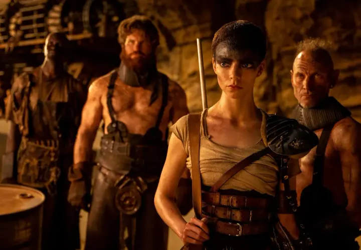 Furiosa z "Sagi Mad Max" w otoczeniu groźnych towarzyszy, gotowa do walki w postapokaliptycznym świecie.