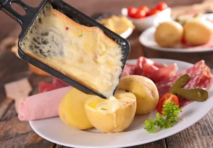 Une idée raclette originale : du fromage fondu coulant sur des pommes de terre, charcuterie et cornichons.