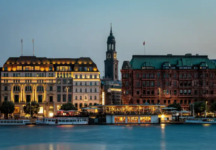 Wieczorny widok na port w Hamburgu, gdzie tętni życie, a budynki oświetlone tworzą malowniczy krajobraz.
