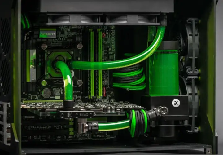 Sistema de refrigeración líquida con tubos verdes brillantes y un depósito lleno de líquido fluorescente, integrado en un PC de alto rendimiento.