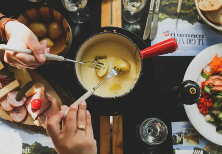 Un délicieux moment de partage autour d'une fondue savoyarde, accompagnée d'un verre de riesling. Des pommes de terre et de la charcuterie complètent ce festin.
