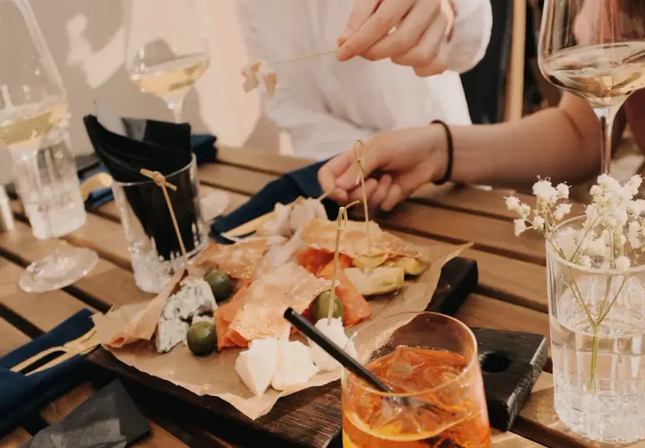 Leckereien auf einer Holzplatte, wie auf einer food pairing tabelle. Dazu Weißwein und ein Aperol Spritz.