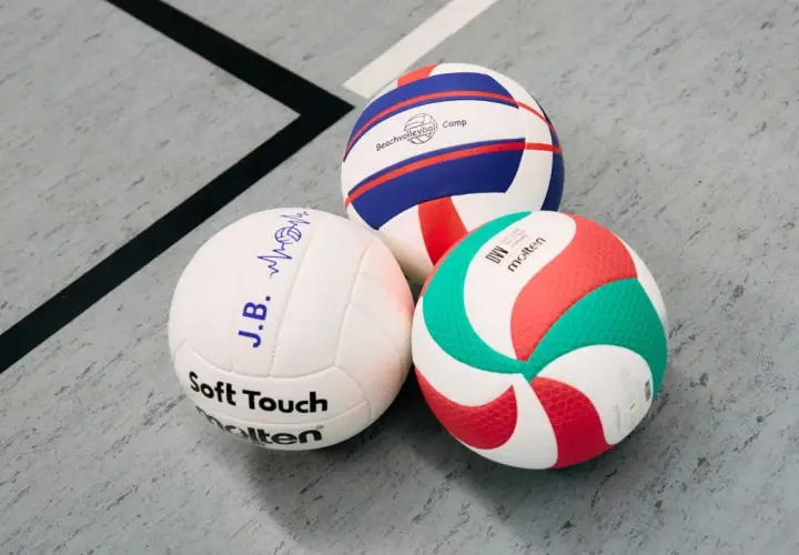 Trzy piłki siatkowe: biała z napisem "Soft Touch", biało-niebiesko-czerwona z napisem "Beachvolleyball Camp" i biało-zielono-czerwona Molten.