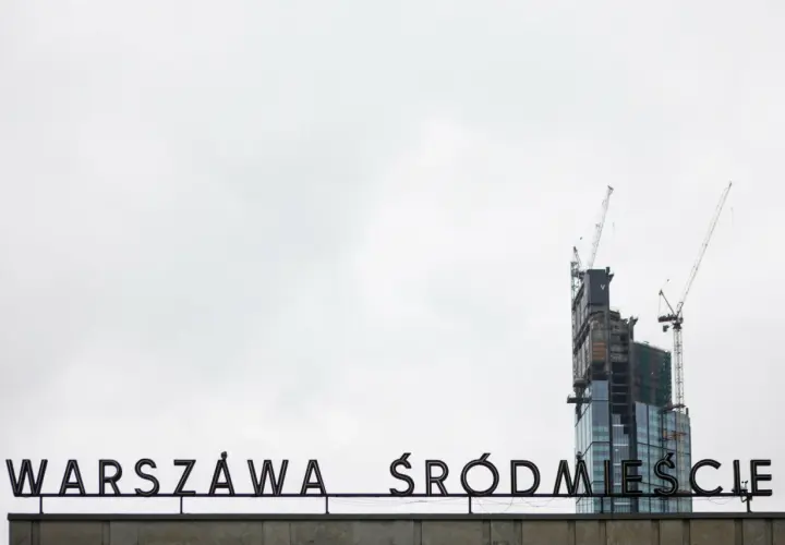 Varso Tower w budowie z dźwigami, na tle napisu "WARSZAWA ŚRÓDMIEŚCIE".