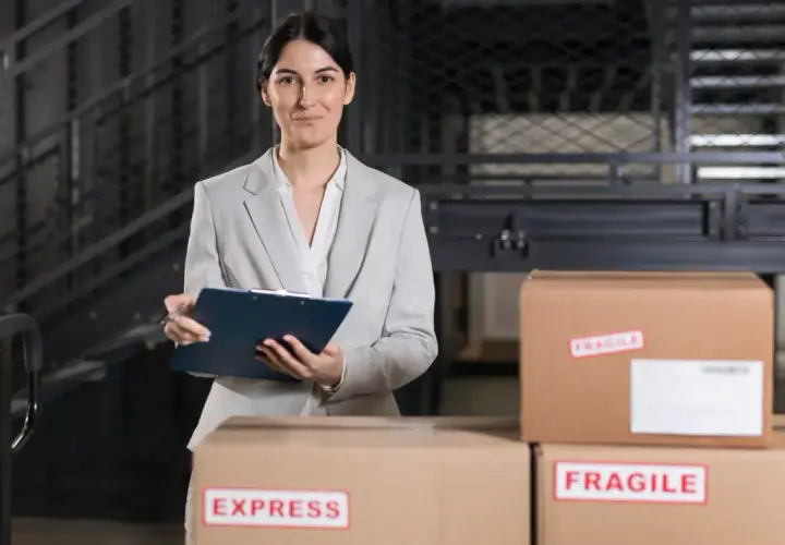 Agent celny z notatnikiem w ręku nadzoruje przesyłki, w tym oznaczone jako "EXPRESS" i "FRAGILE".