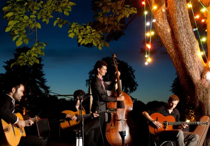 Un groupe de musique joue sous les lumières de Noël. Le contrebassiste est au centre, entouré de guitaristes. Un prix pour ce groupe de musique serait bien mérité.