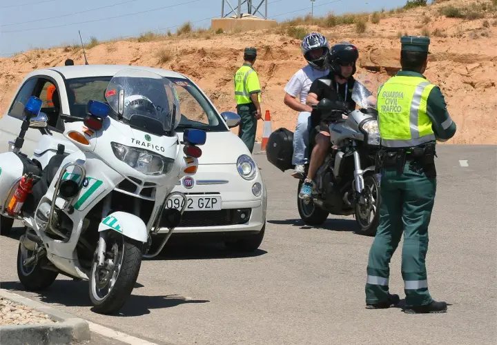 Agente de tráfico detiene a motoristas. Posible multa por llevar pasamontañas.