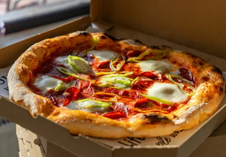 Pyszna pizza z pepperoni, mozzarellą i papryką, która przypomina o bogatej historii pizzy.