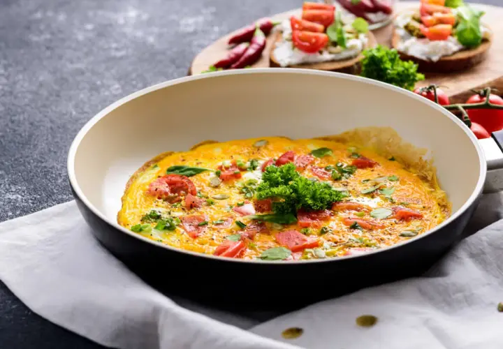 Omlet z pomidorami i ziołami na patelni. Idealny sposób, jak ograniczyć węglowodany w diecie.