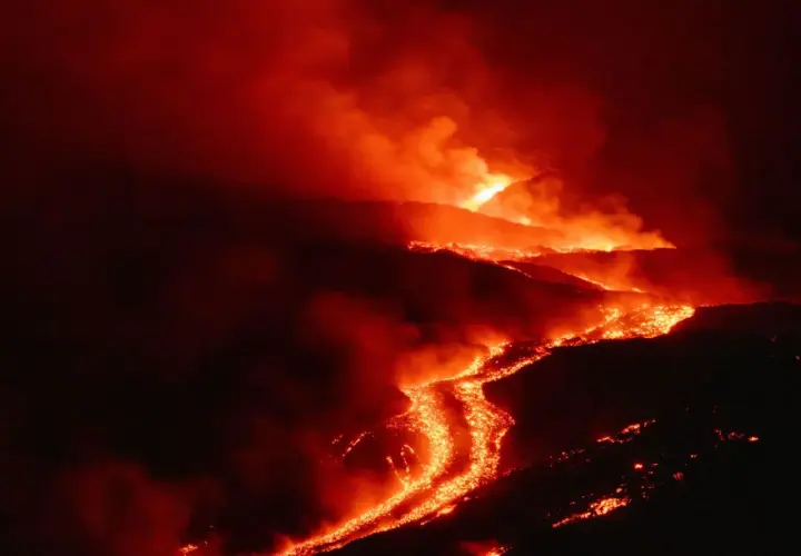 Glühende Lava fließt den Hang eines Vulkans auf Sizilien hinab, umgeben von Rauch und Dunkelheit.