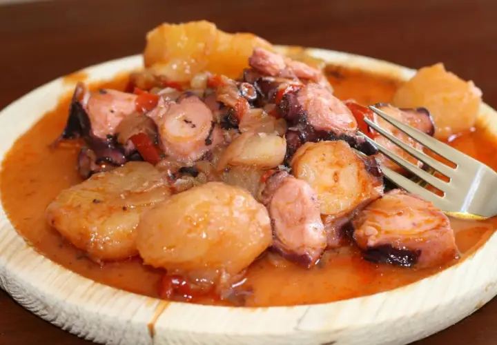 Pulpo a la mugardesa, un plato gallego con trozos de pulpo tierno y patatas cocidas en una salsa rojiza.