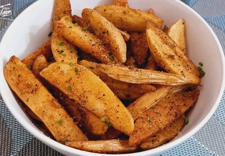 Un tazón lleno de patatas deluxe crujientes, sazonadas con especias y hierbas frescas.