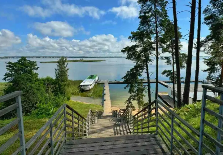 Drewniane schody prowadzą do jeziora, gdzie cumuje statek. Idealne miejsce, by zapytać: gdzie na Mazury?
