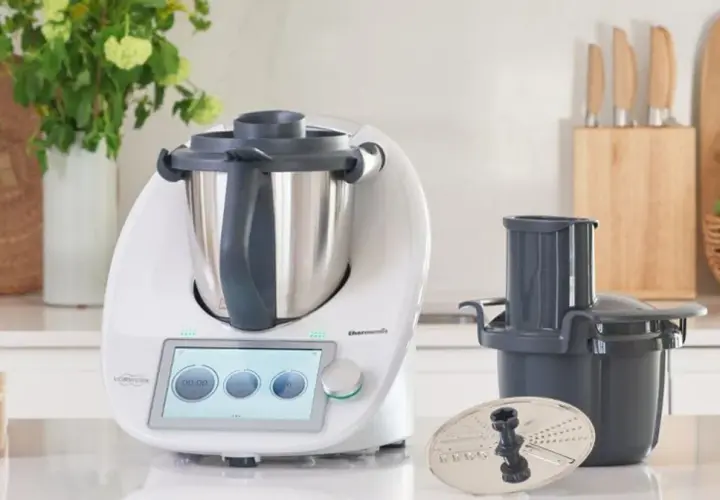 Biały Thermomix z ekranem dotykowym, akcesoriami i warzywami na blacie. Zastanawiasz się, ile wat ma Thermomix?