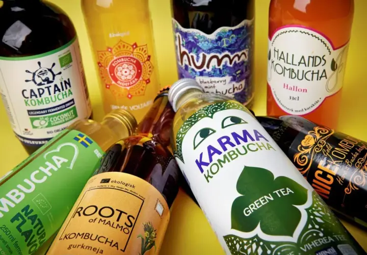 Flera flaskor kombucha, en dryck som många anser vara nyttig, ligger utspridda. Olika märken som Captain Kombucha, Karma Kombucha och Hallands Kombucha syns.