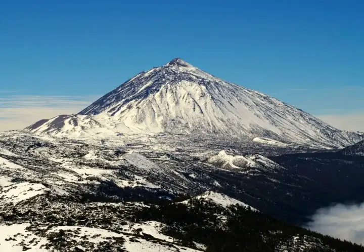 Schneebedeckter Teide-Vulkan auf Teneriffa im Dezember, ein beeindruckender Anblick über den Wolken.