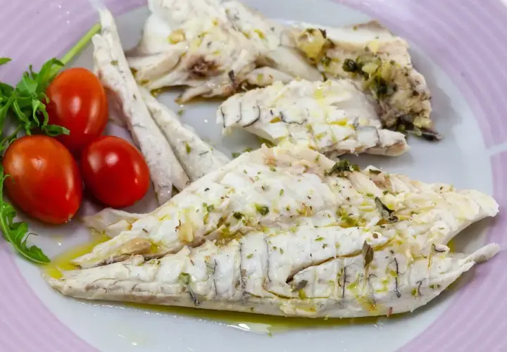 Delizioso branzino in padella, cotto alla perfezione e condito con erbe aromatiche. Servito con pomodorini freschi e rucola.