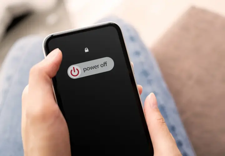Dłoń trzyma telefon z ekranem blokady, na którym widnieje przycisk "power off". Dowiedz się, jak wyłączyć telefon realme.