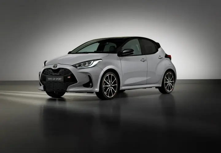 Srebrny Toyota Yaris GR Sport z czarnym dachem i sportowymi felgami stoi na ciemnej podłodze.