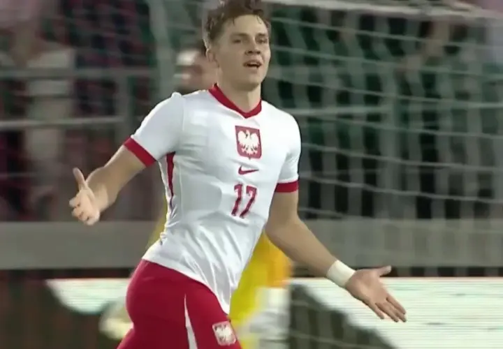 Młody piłkarz w białej koszulce z numerem 17 i godłem Polski cieszy się z bramki.
