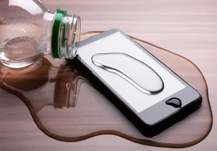 Telefon wpadł do wody, ale działa! Kropla wody na ekranie, a obok butelka.