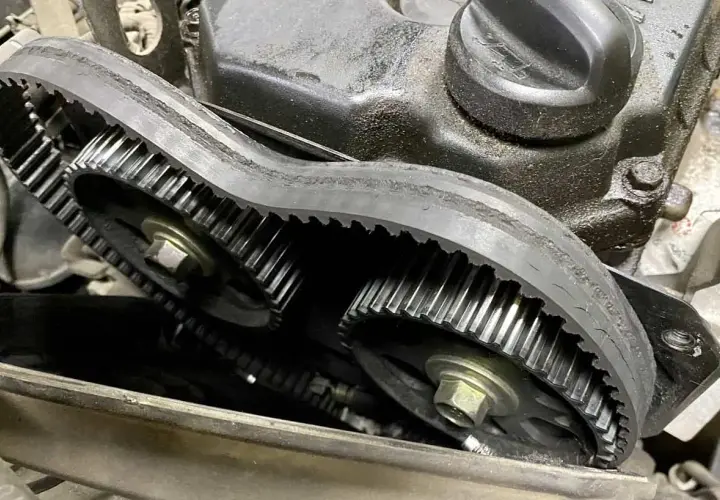 Widok na zębatki silnika z zerwanym paskiem rozrządu. Pasek jest luźny i uszkodzony, co uniemożliwia prawidłowe działanie mechanizmu.