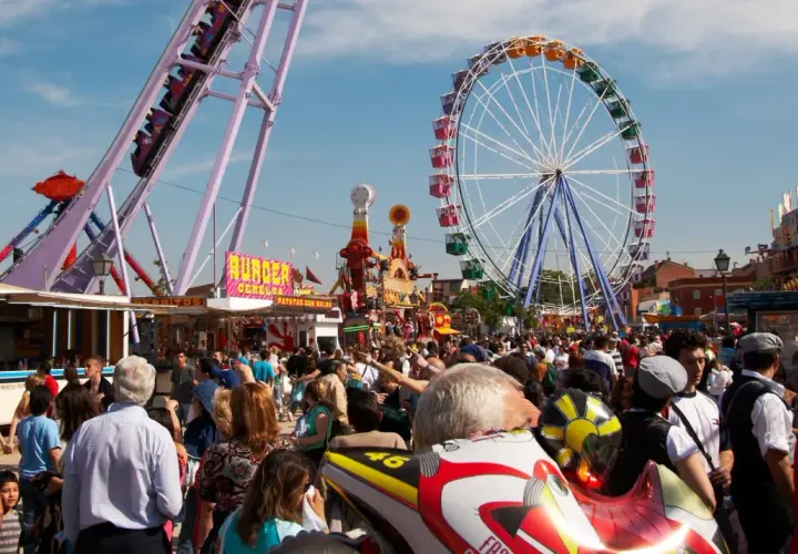 Feria en la Finca San Isidro Madrid con noria, atracciones y mucha gente disfrutando del día.