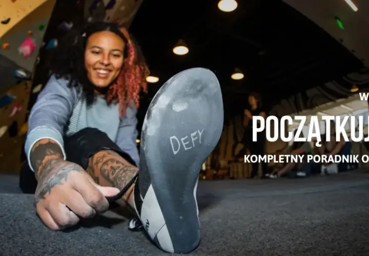 Uśmiechnięta kobieta zakłada buty do wspinaczki na ściance. Dowiedz się, bouldering co to jest i jak zacząć.