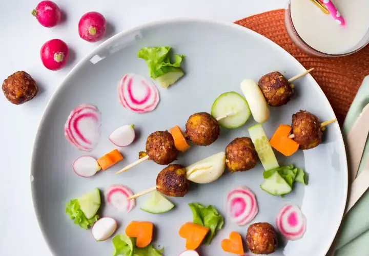 Vegetarisk mat för barn: Spett med vegetariska köttbullar, gurka, morötter och rädisor. En festlig och färgglad måltid.