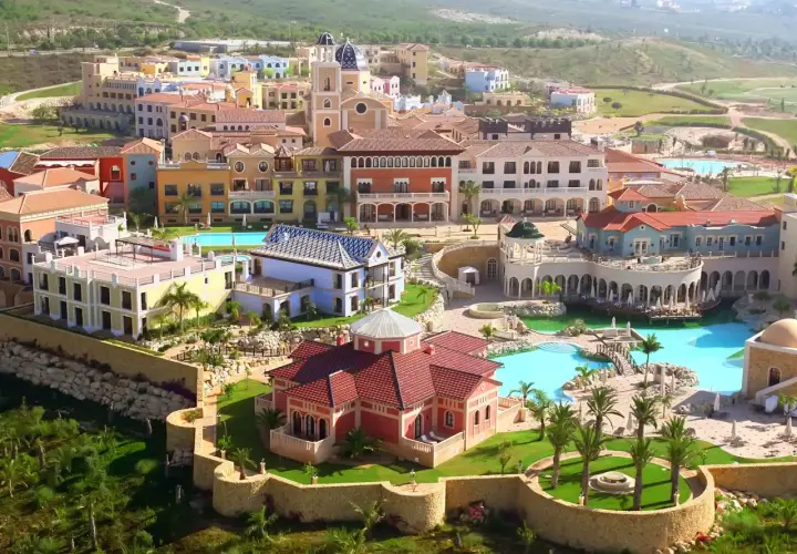 Vista aérea del hotel Villaitana en Benidorm, con sus coloridos edificios, piscinas y exuberante vegetación.