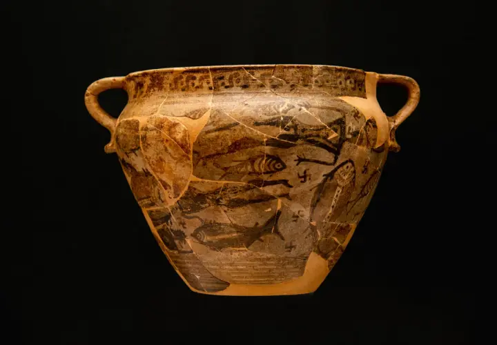 Antico vaso greco con decorazioni di pesci e figure, forse un'opera ispirata a **Giorgio Buchner**. Frammentato ma affascinante.