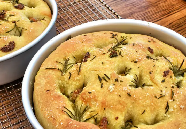 Focaccia senza glutine dorata, con rosmarino e sale grosso, appena sfornata e pronta per essere gustata.