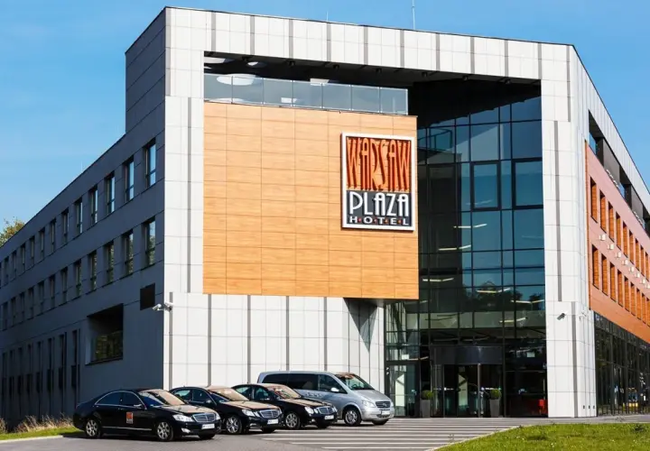Warsaw Plaza Hotel z nowoczesną fasadą i zaparkowanymi samochodami.